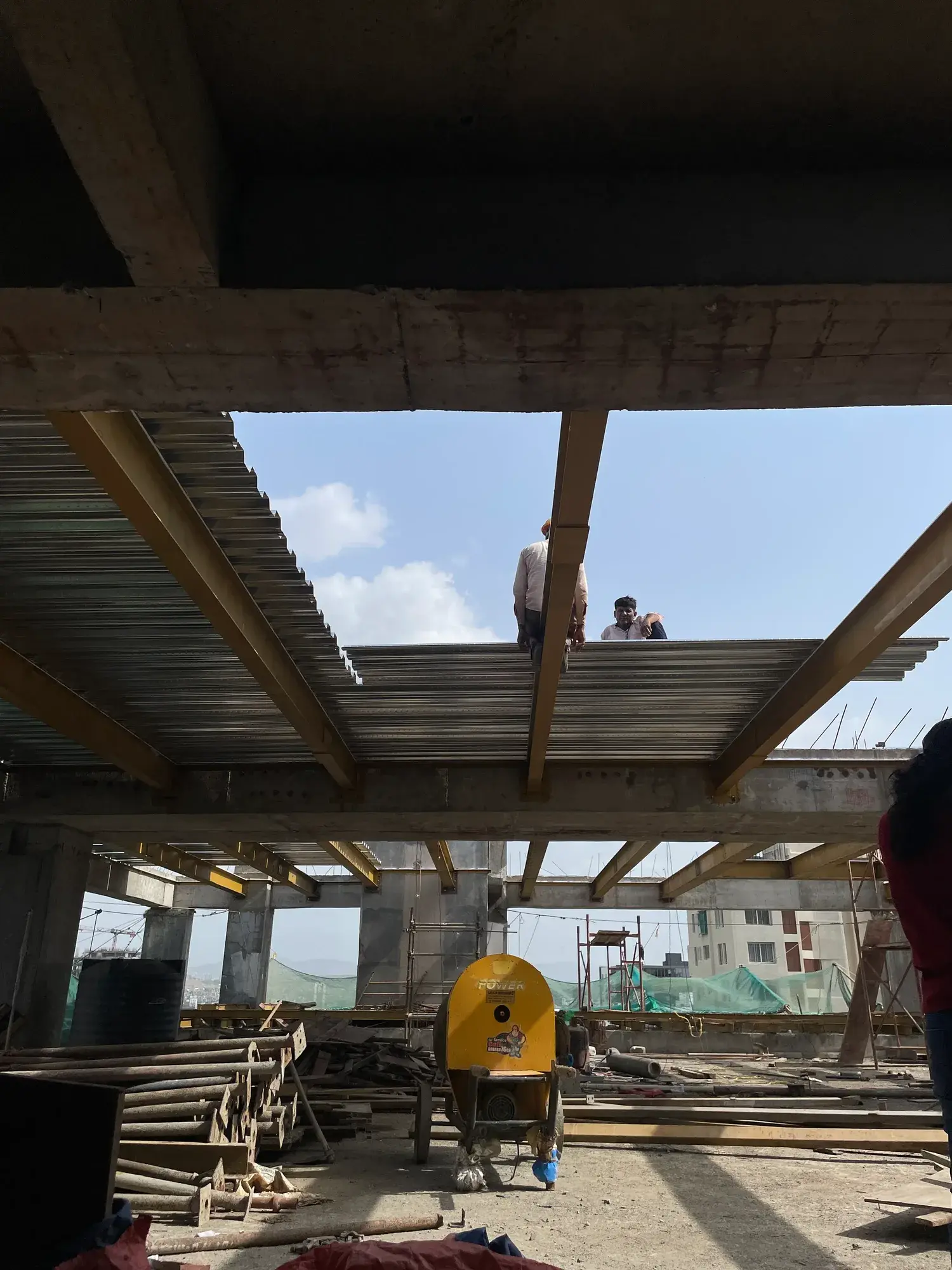 Metal decking sheets being laid over the beam framework at Kalpvishwa